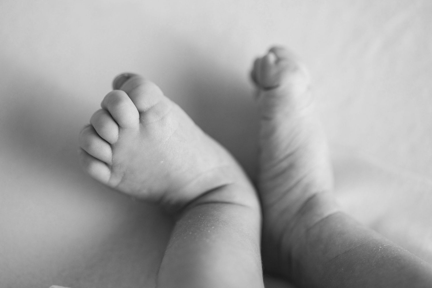A series of black and white photographs showing tiny baby feet against a soft background.
