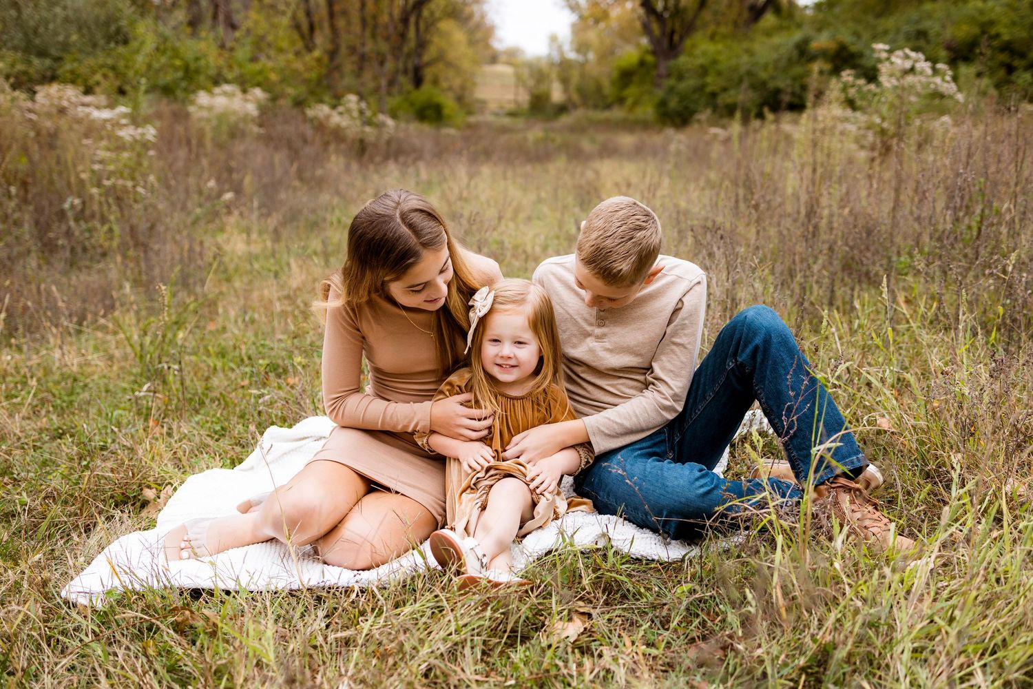 A couple lies together in a grassy meadow during a romantic outdoor photoshoot at golden hour.