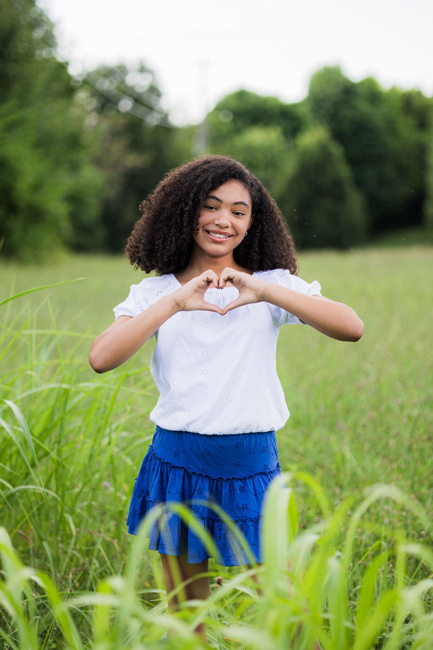 A playful sequence of someone in a white top and blue skirt posing in a grassy meadow.