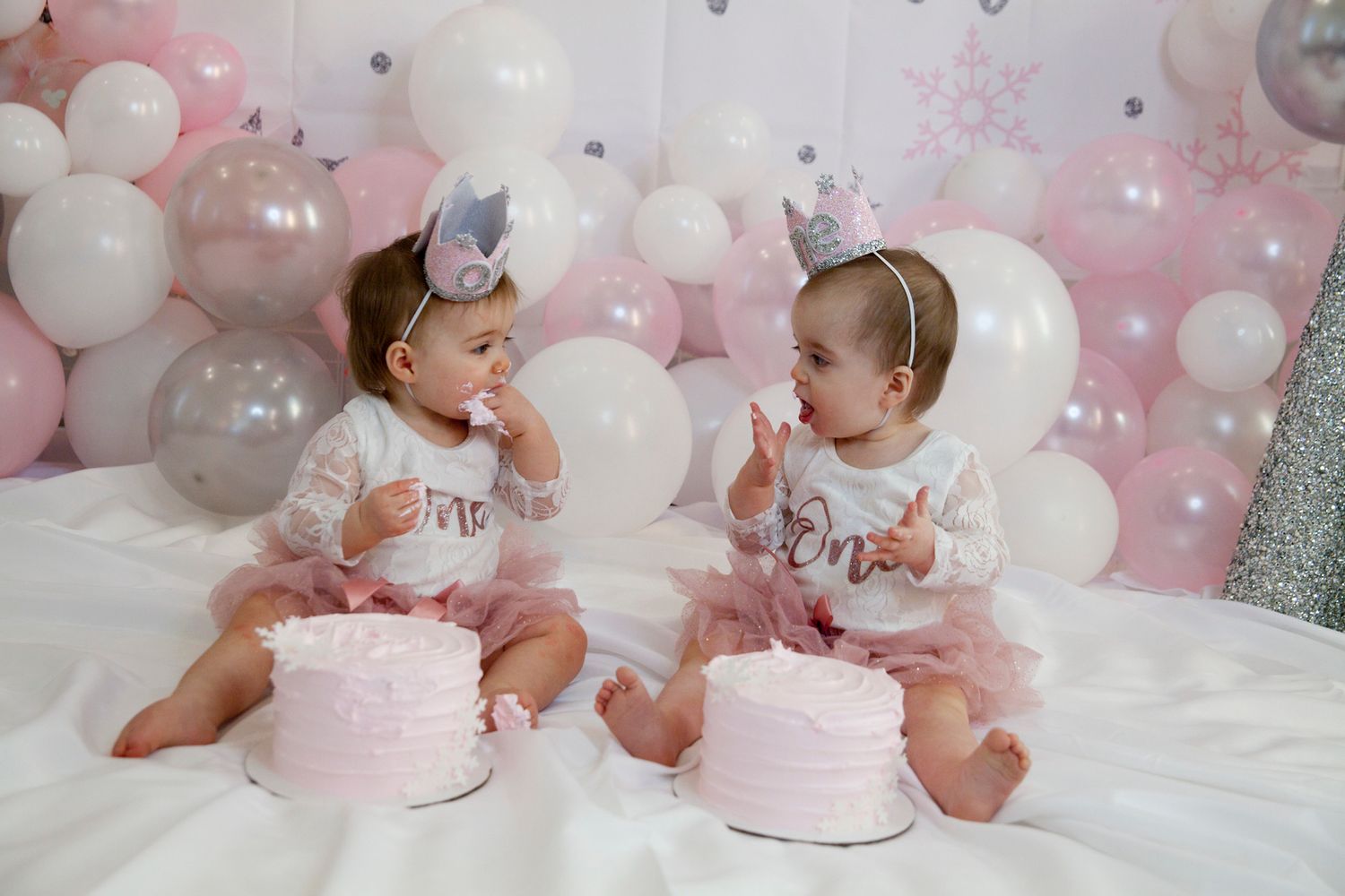 Pink and white balloon decorations with cake smash setup for a baby's first birthday celebration.