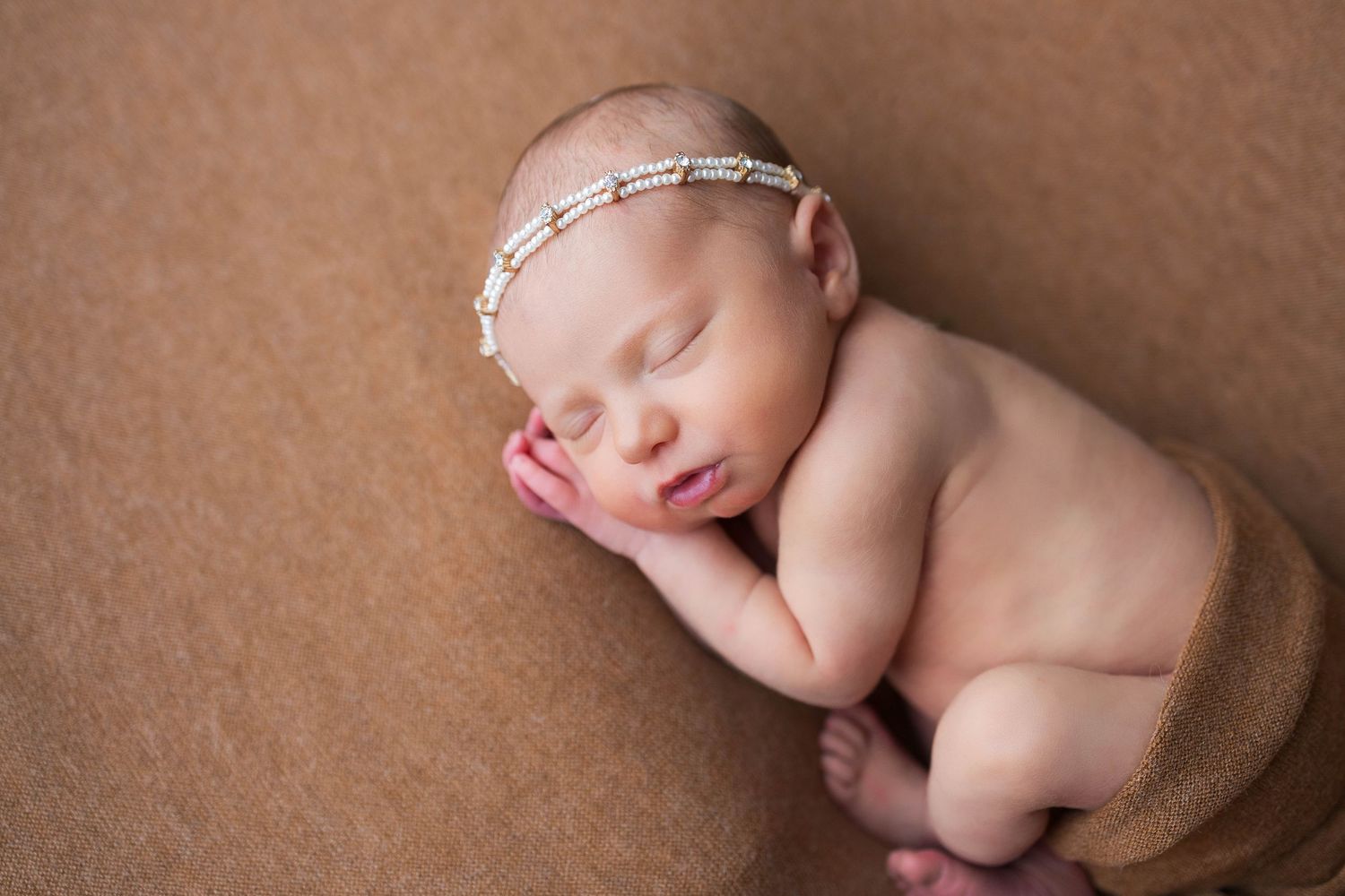 A collection of newborn baby portraits showing peaceful sleeping poses on a brown textured backdrop.
