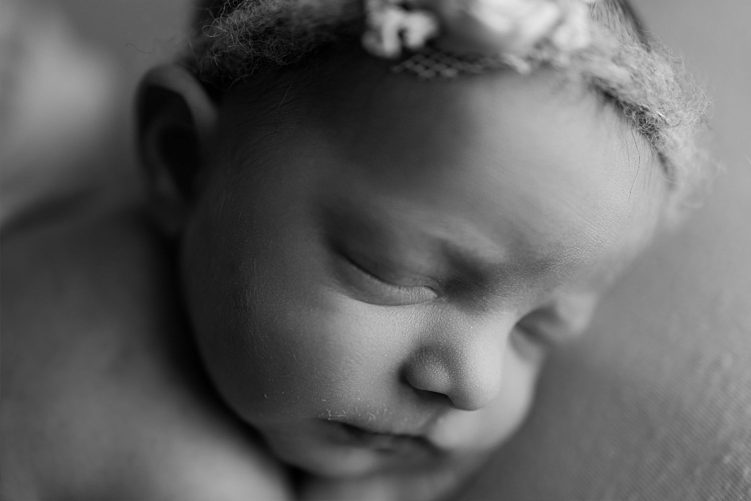 Black and white close-up portrait of sleeping newborn with delicate headband.