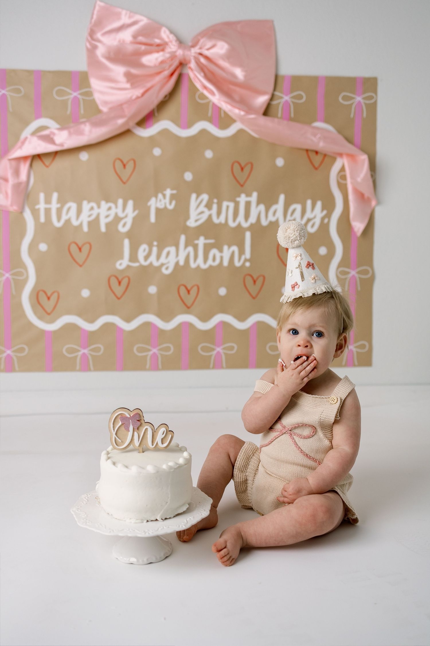Pink and kraft paper birthday backdrop with white cake and festive party decorations.