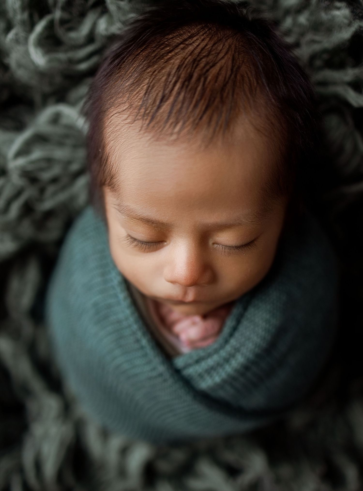 A series of artistic newborn portraits in teal tones showing peaceful sleeping poses and gentle expressions.