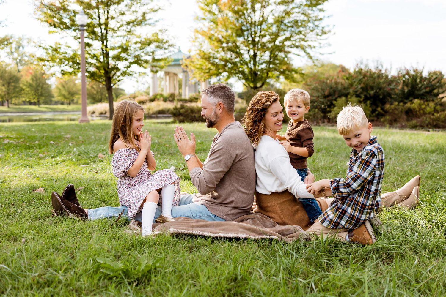 A group lounges together on a grassy hill during a sunny autumn afternoon.
