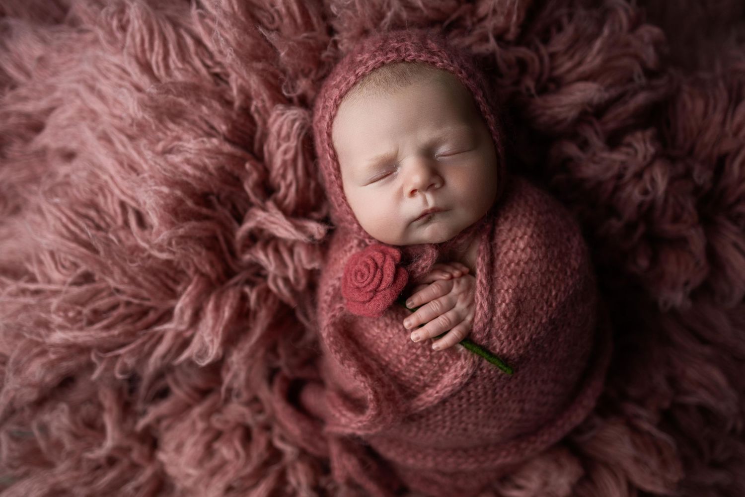 Newborn baby in mauve knit wrap photographed from multiple angles on soft pink fur backdrop.