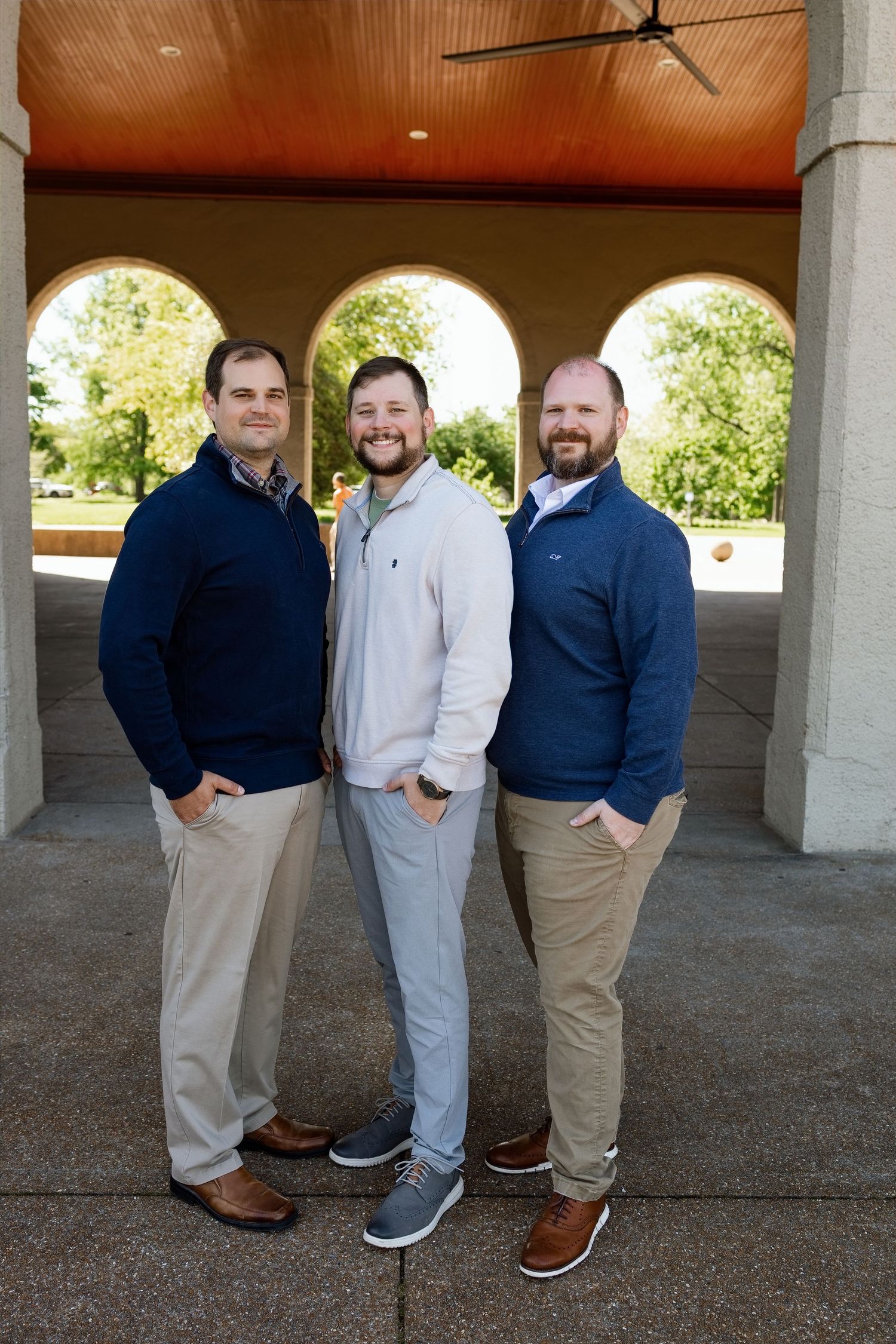 Three men smiling together beneath an outdoor pavilion during a family photography session near Edwardsville