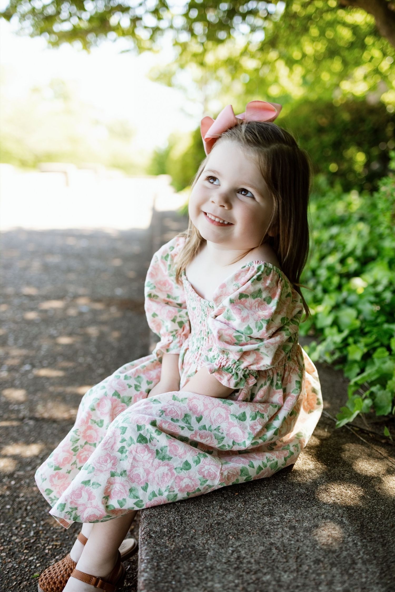 Young girl smiling in a floral dress during an outdoor child portrait session near Edwardsville