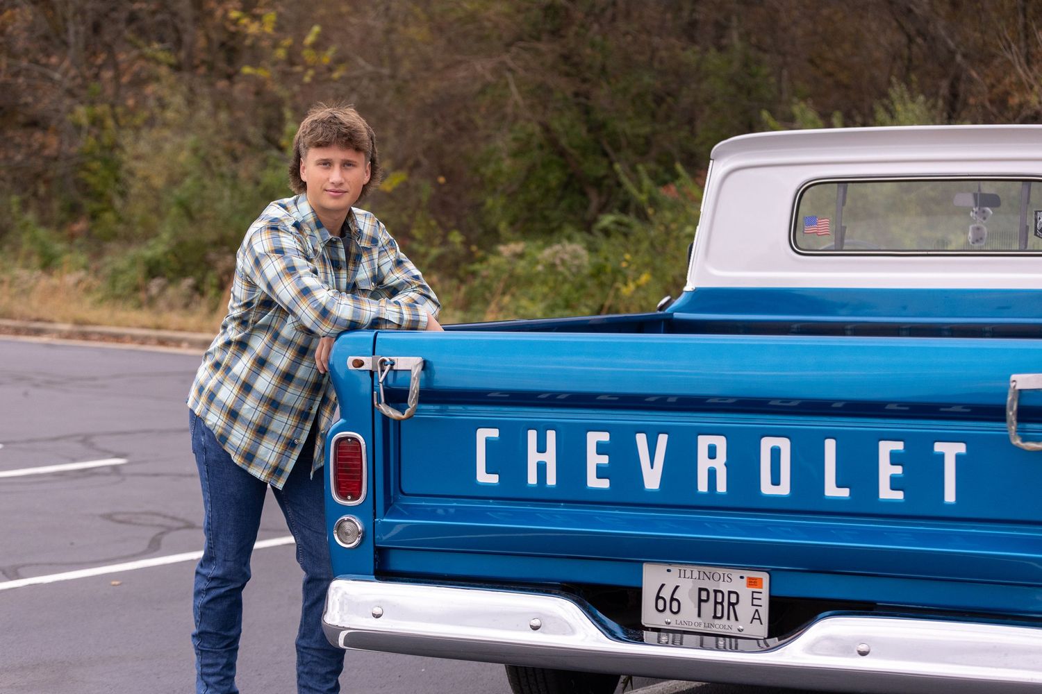 Person leaning on tailgate of vintage blue Chevrolet pickup truck.