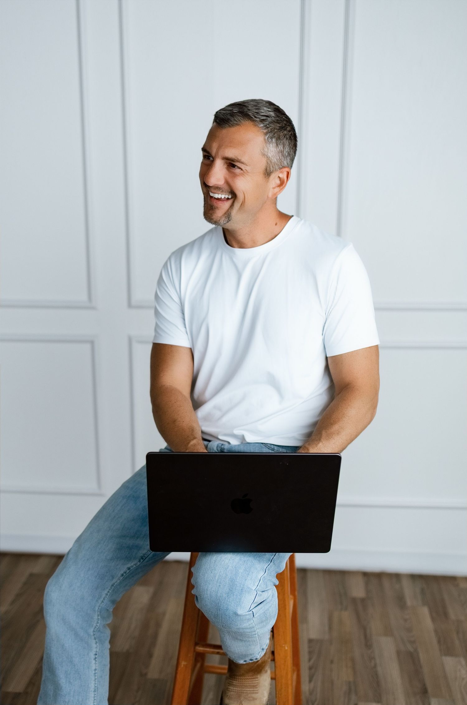 Male podcast host seated with a laptop during an individual professional-brand portrait in Edwardsville
