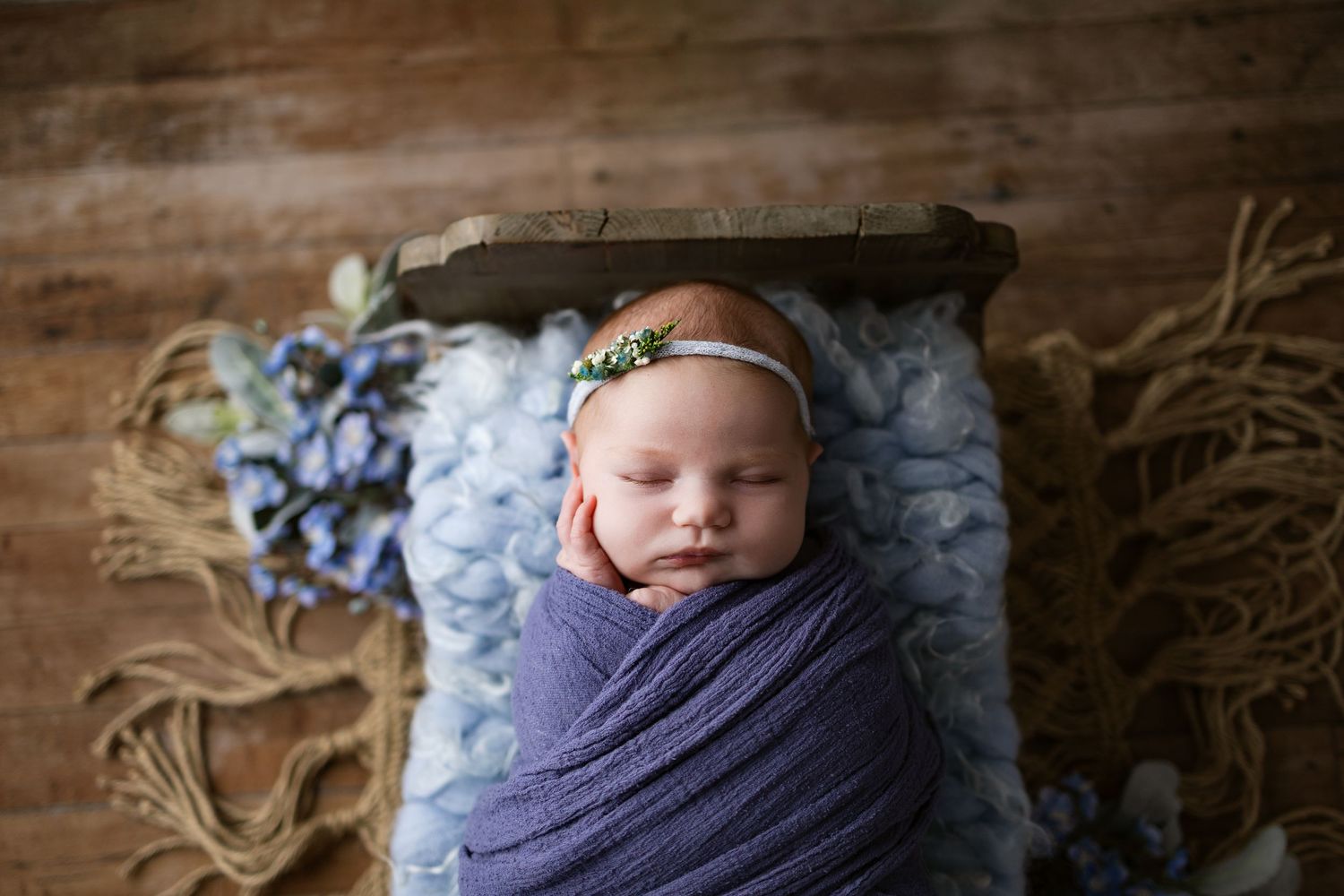 A collage of newborn photography images showing a sleeping baby wrapped in purple and blue swaddle blankets.