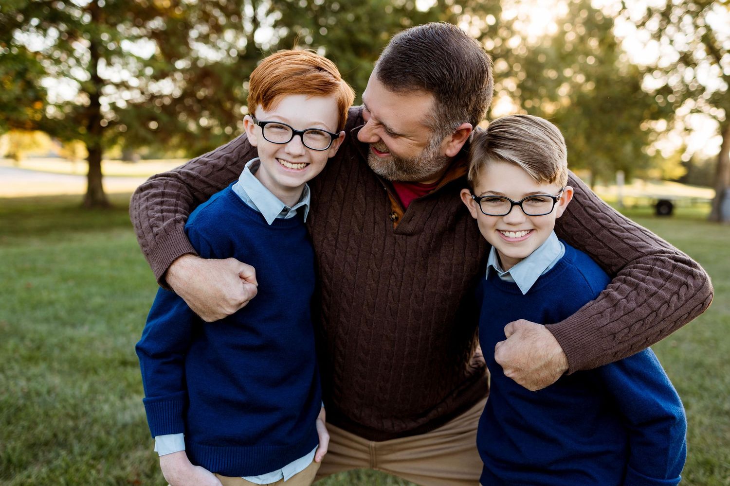 A family shares warm embraces and joyful moments together in a sunlit outdoor setting during golden hour.