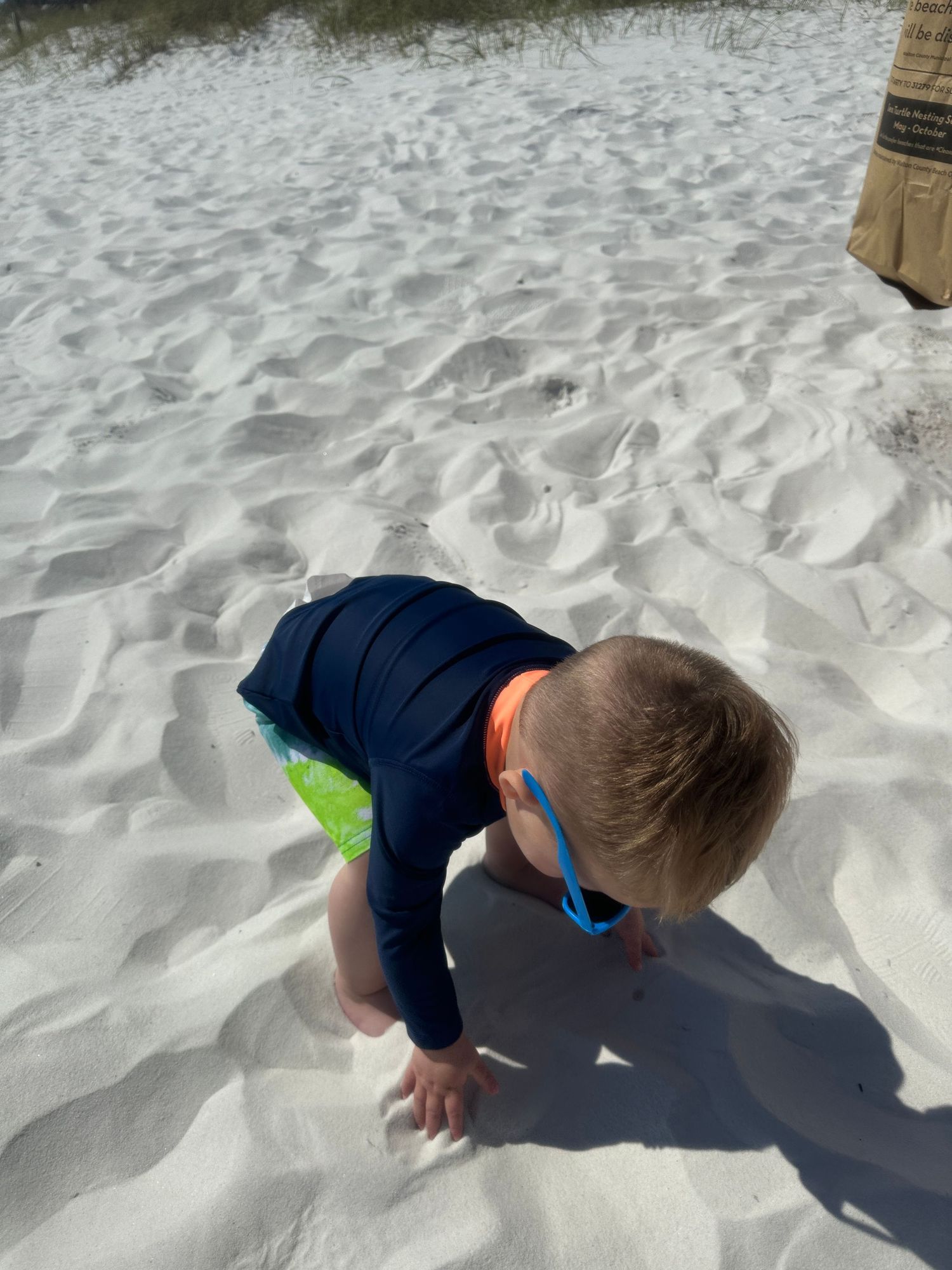 Child playing in white sandy beach on a bright sunny day.