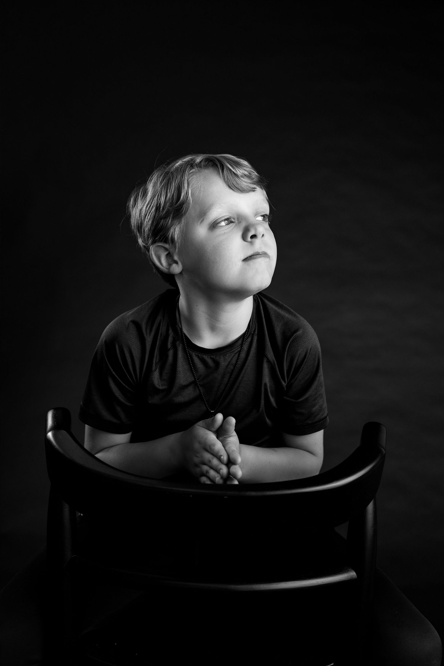 Black-and-white portrait of a young boy looking upward during a dramatic milestone photography session in Edwardsville