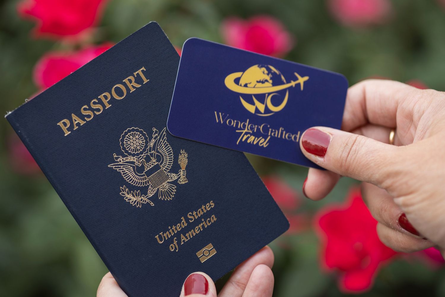 Someone holds a series of US passports fanned out against a background with red flowers and green foliage.