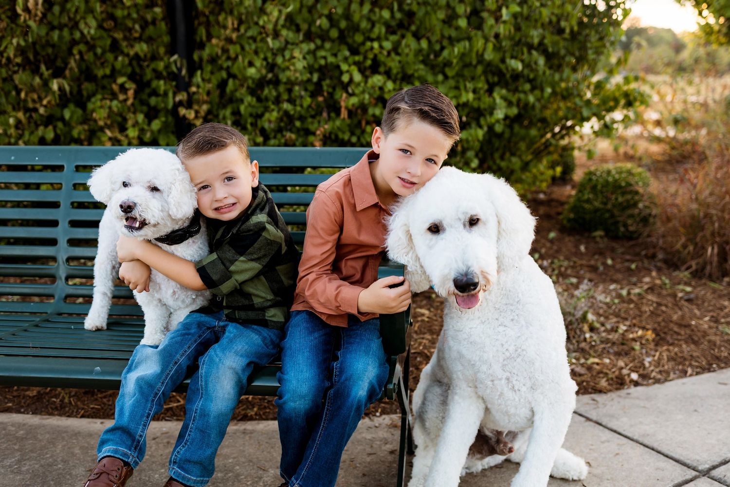 Family sitting together on a blue bench outdoors with their white dog on a sunny day.