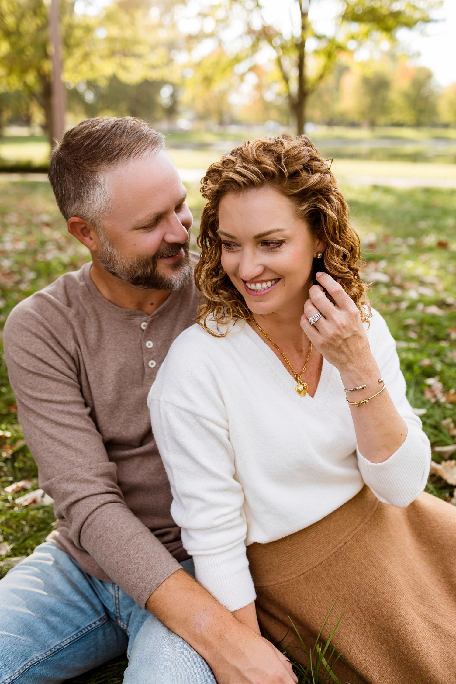 Couple sharing intimate moments while sitting together on grass during autumn.