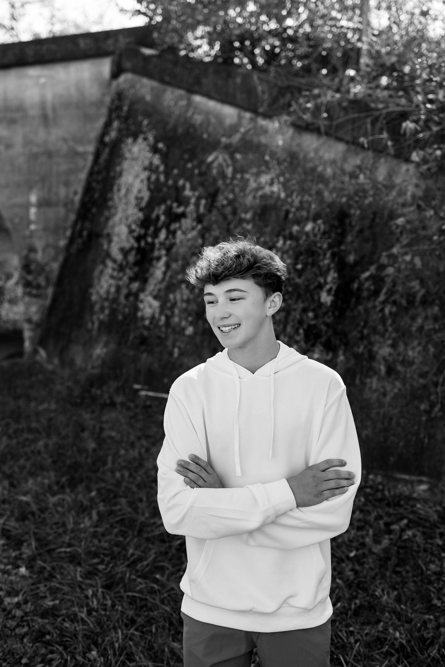 A series of black and white outdoor portraits showing someone in a white sweater against a natural background.