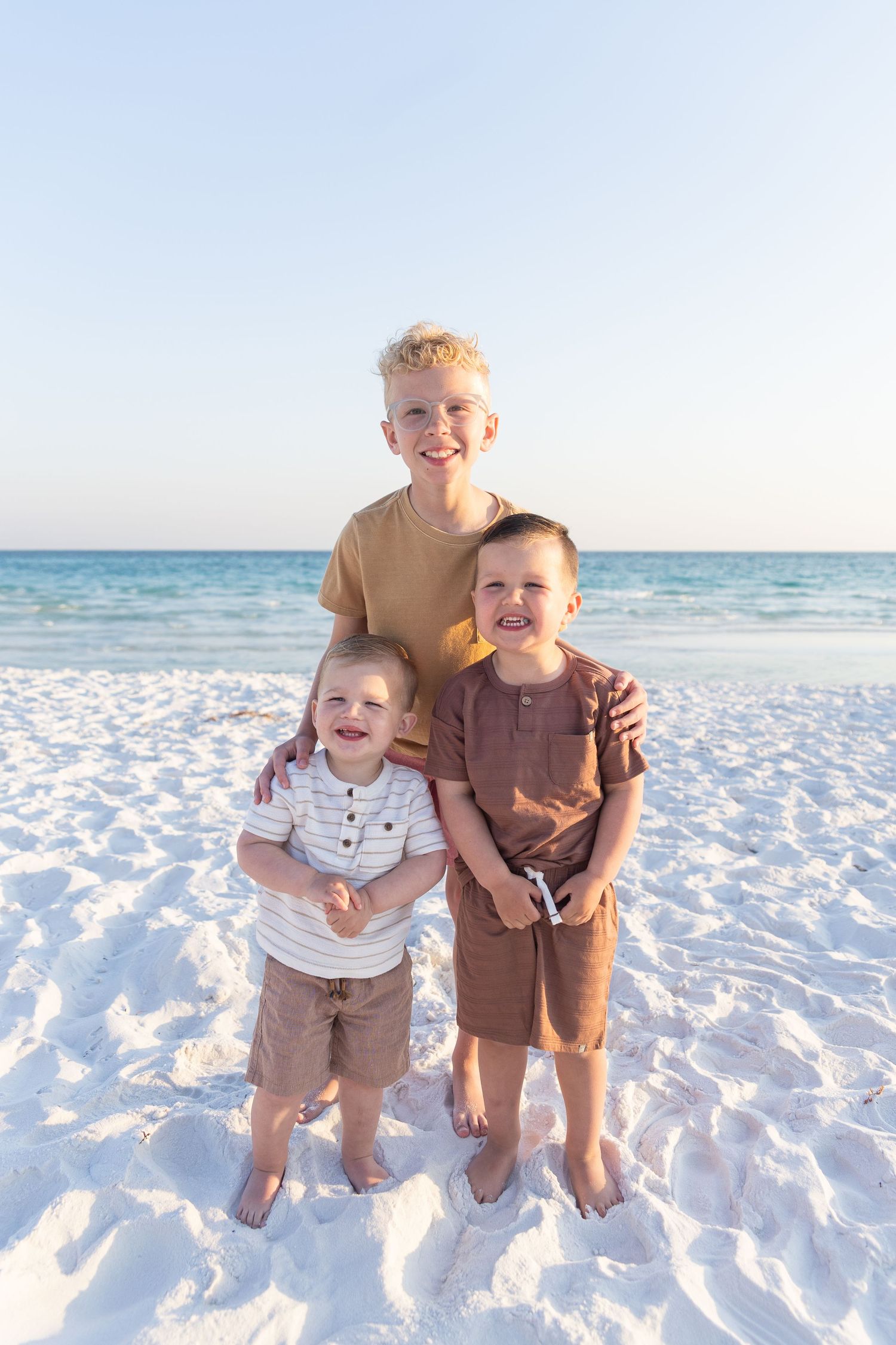 Cheerful group portrait on white sandy beach during sunset with ocean background.