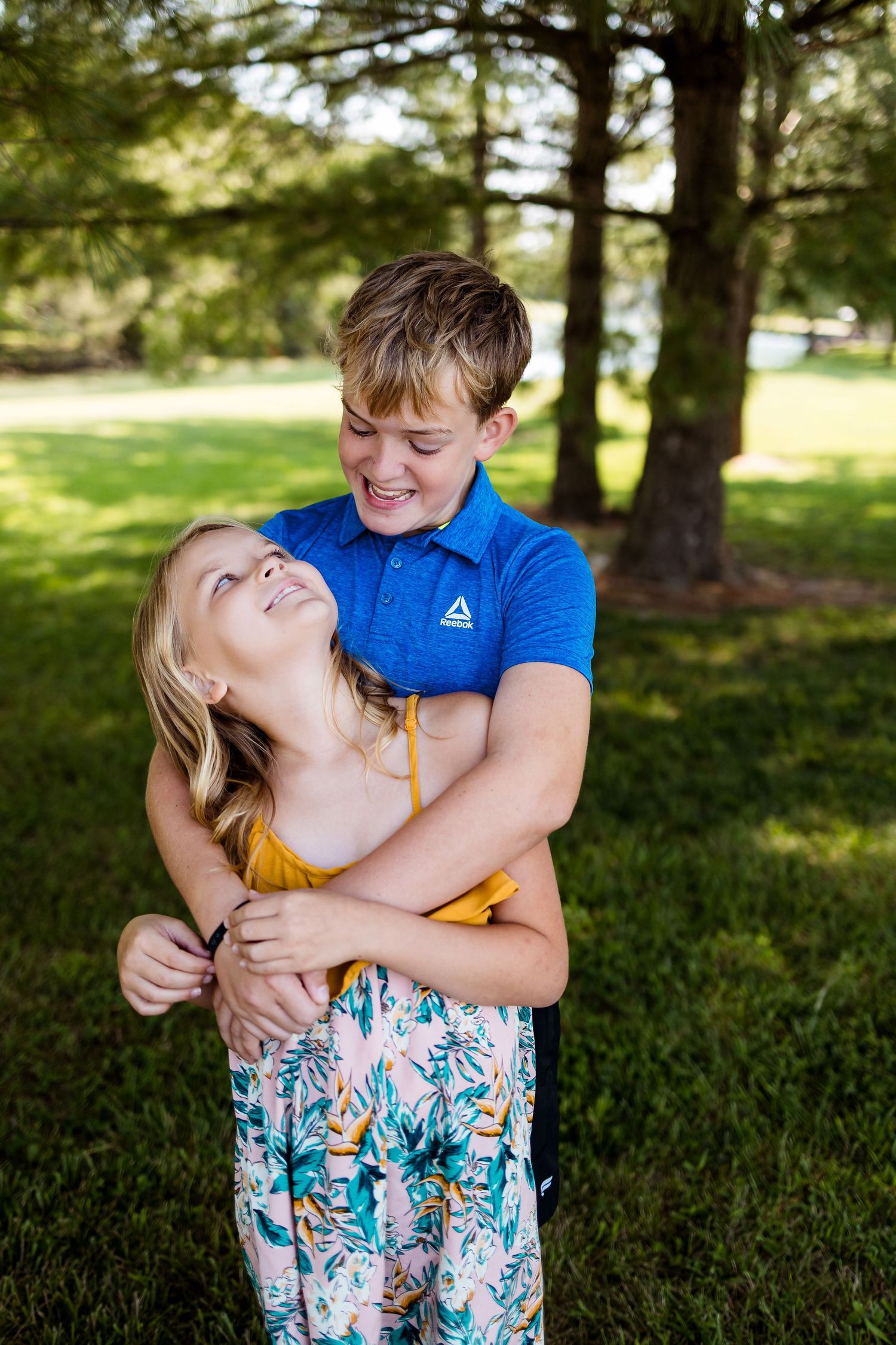 A playful sequence of hugs and affection captured outdoors under shady trees on a sunny day.
