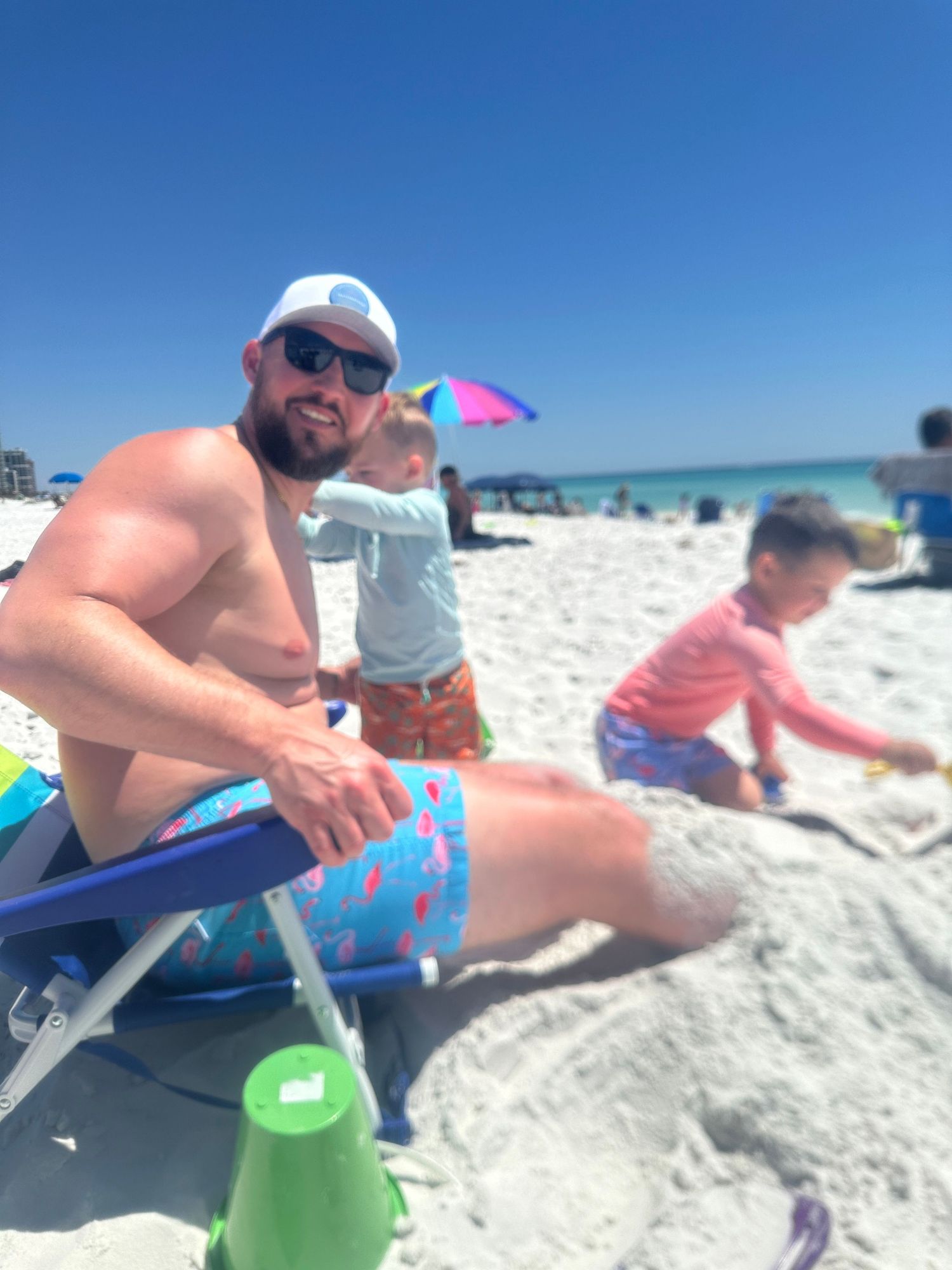 A sunny beach day with colorful beach chairs and toys scattered on white sand.