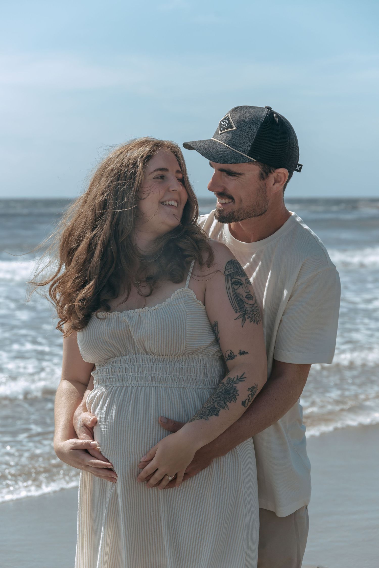 Couple holding baby bump during a beach maternity session