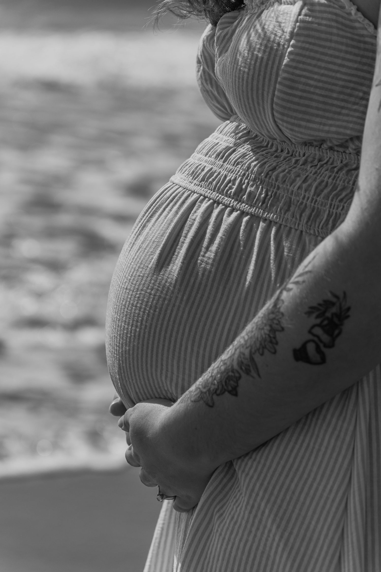 Pregnant mother standing on the beach with ocean in the background