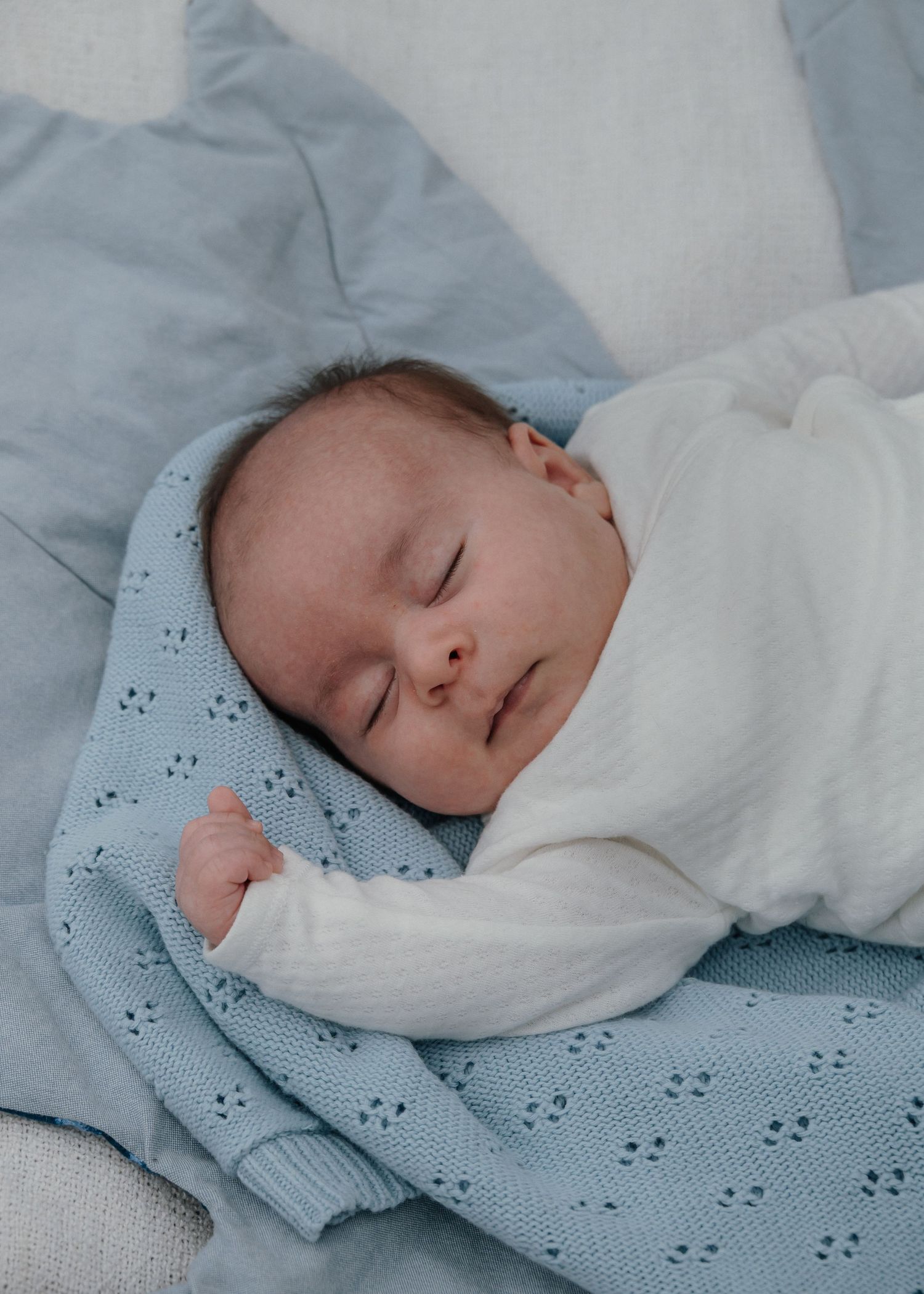 Outdoor newborn photography of a baby resting on blanket.