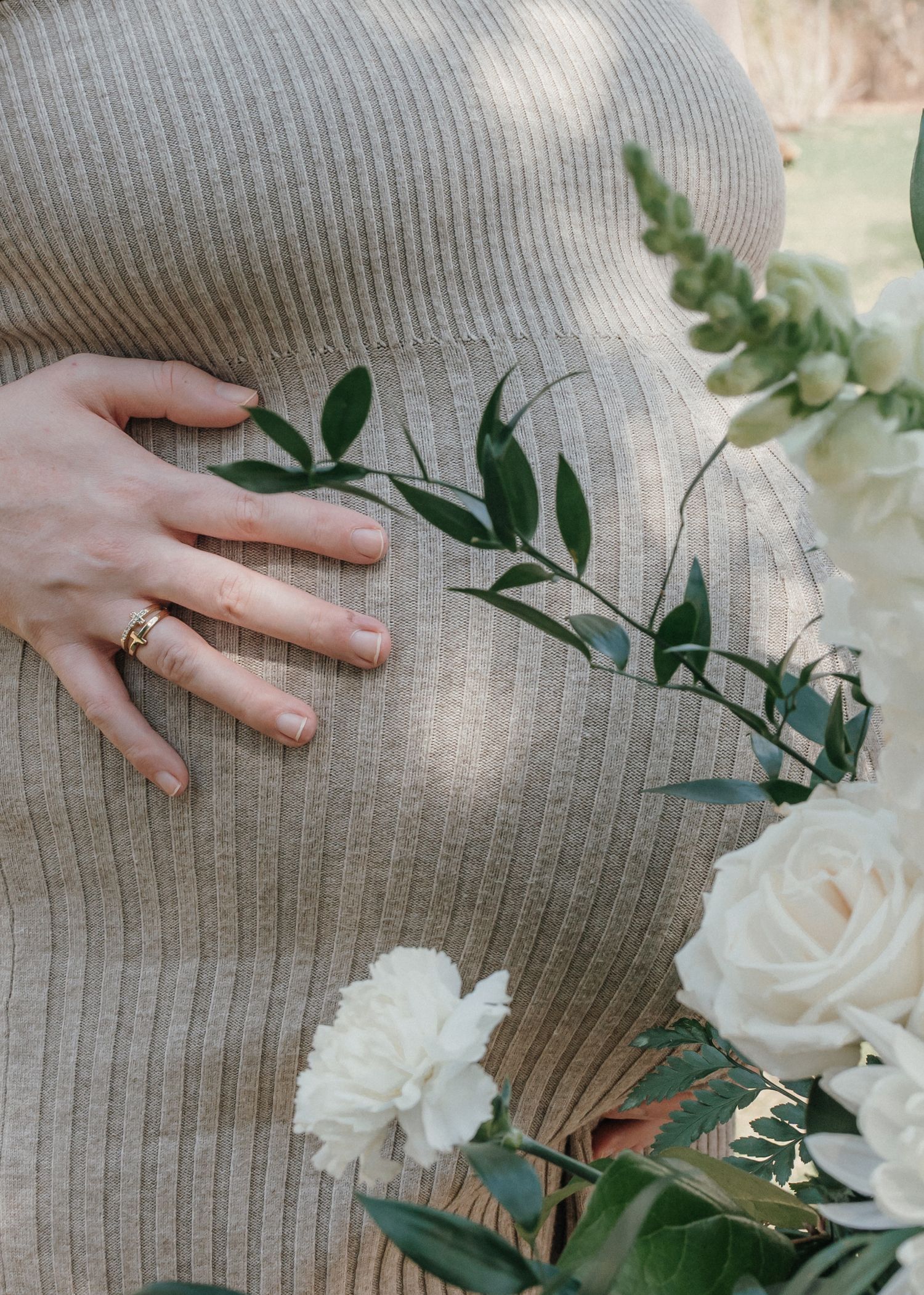 Expecting mother holding baby bump during outdoor maternity session in Prince Edward Island.