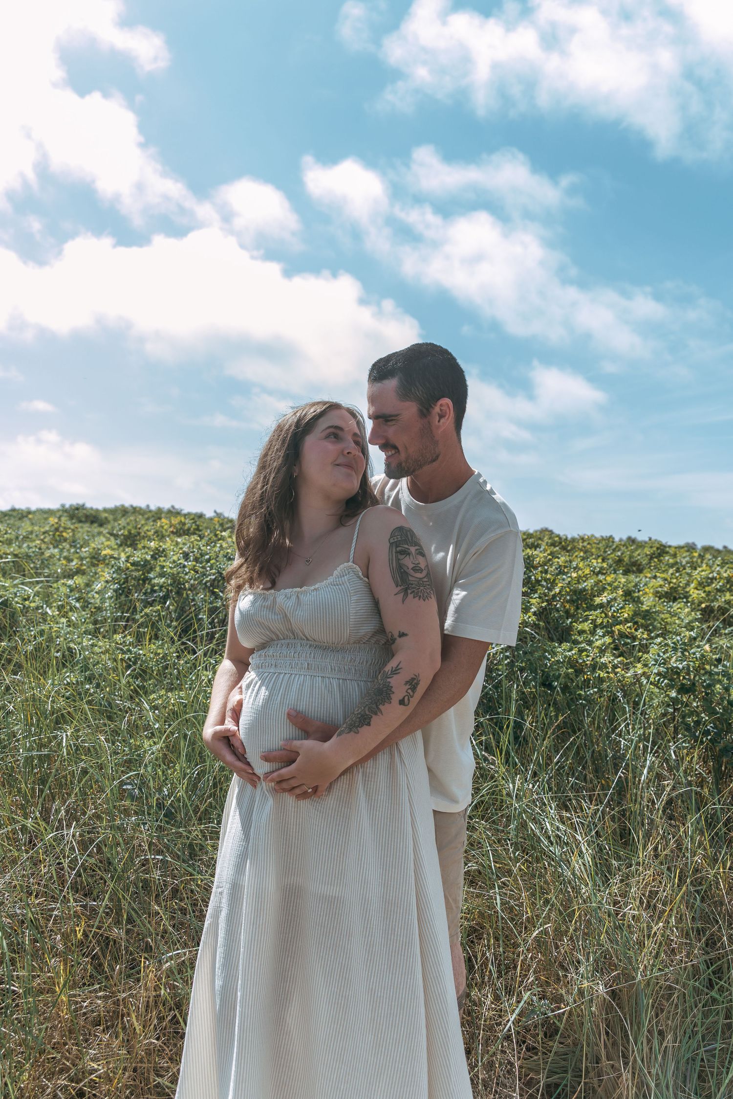 Couple holding baby bump during a beach maternity session