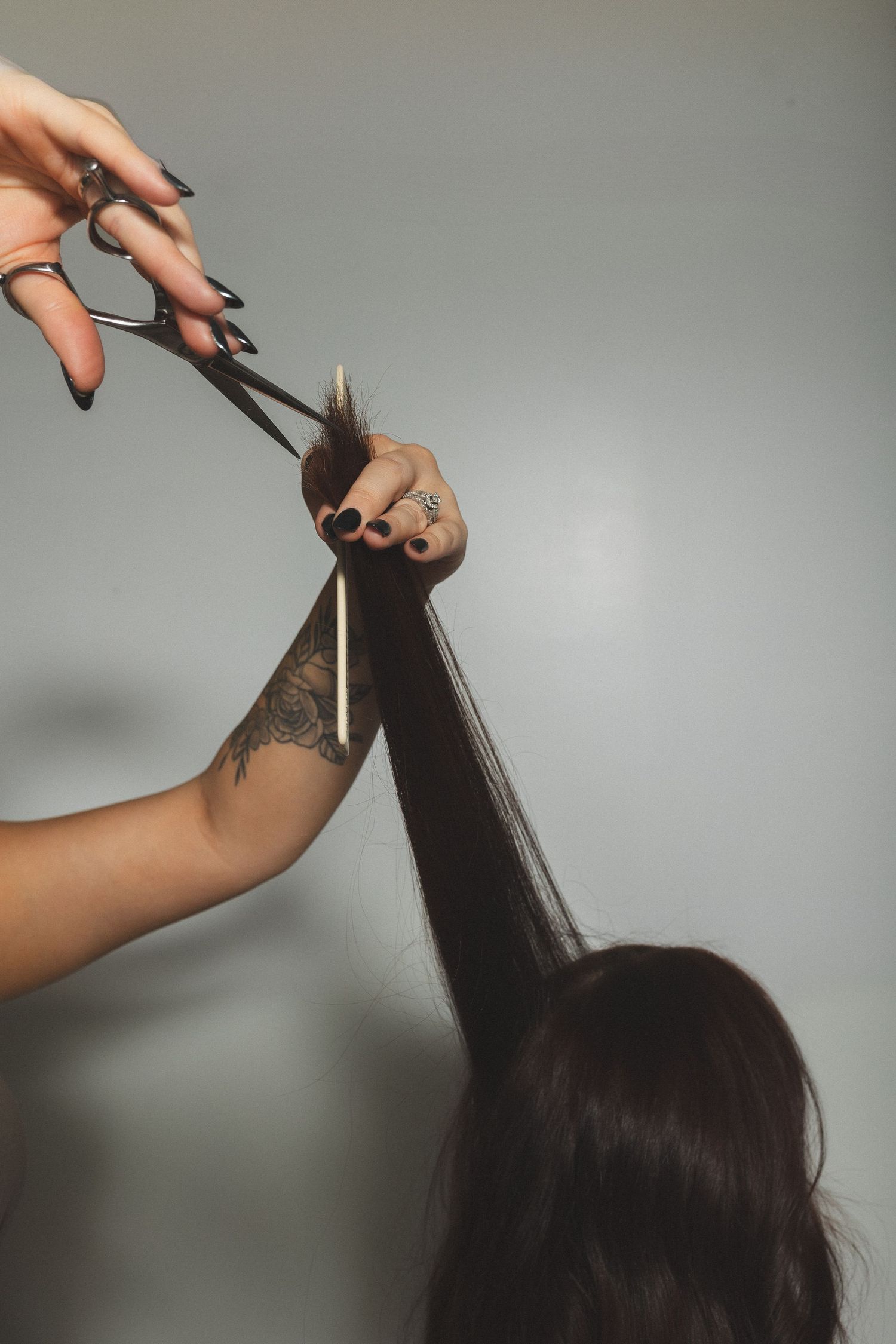 Professional hairdresser using scissors to cut long dark hair.
