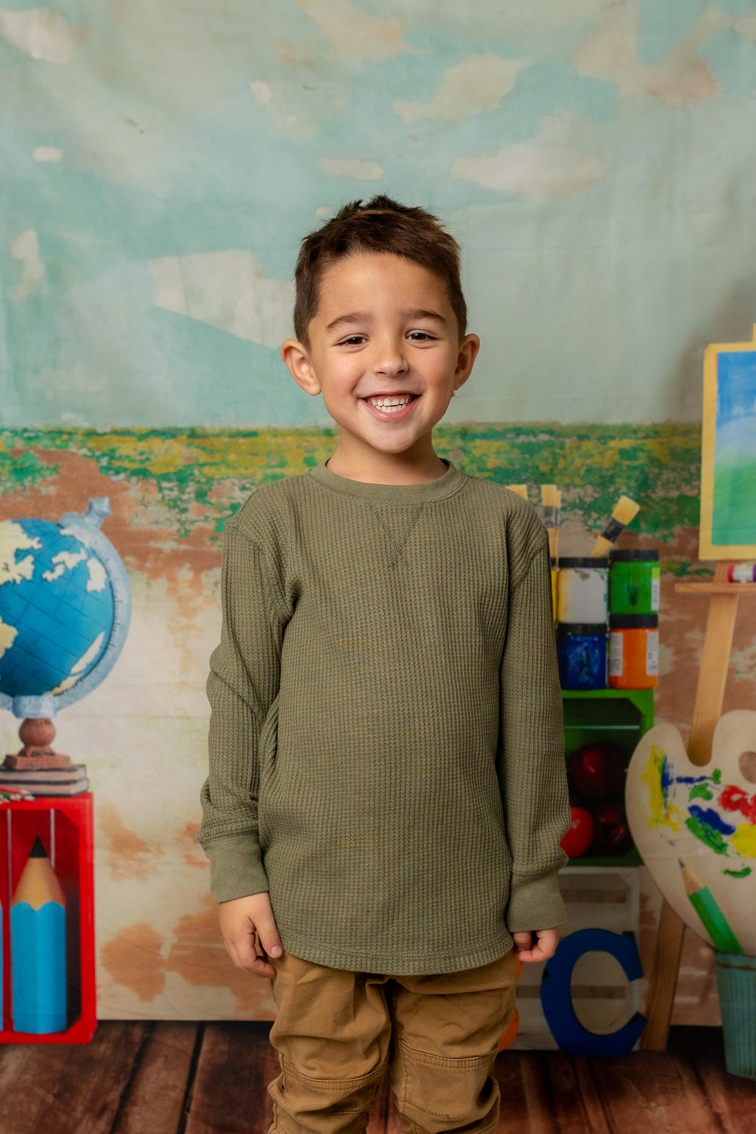 A classroom setting with educational decor including a globe, art supplies and colorful wooden backdrop.