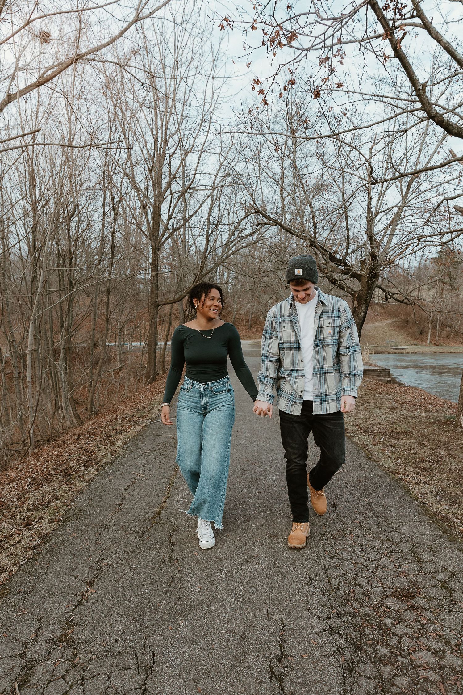 Hand-in-hand on a wooded path, relaxed couple photo with storytelling connection and soft vintage film edit.