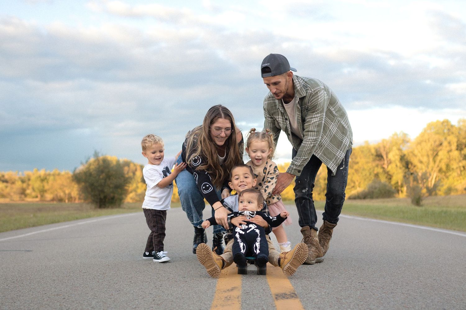 Family playing together on a country road during sunset.