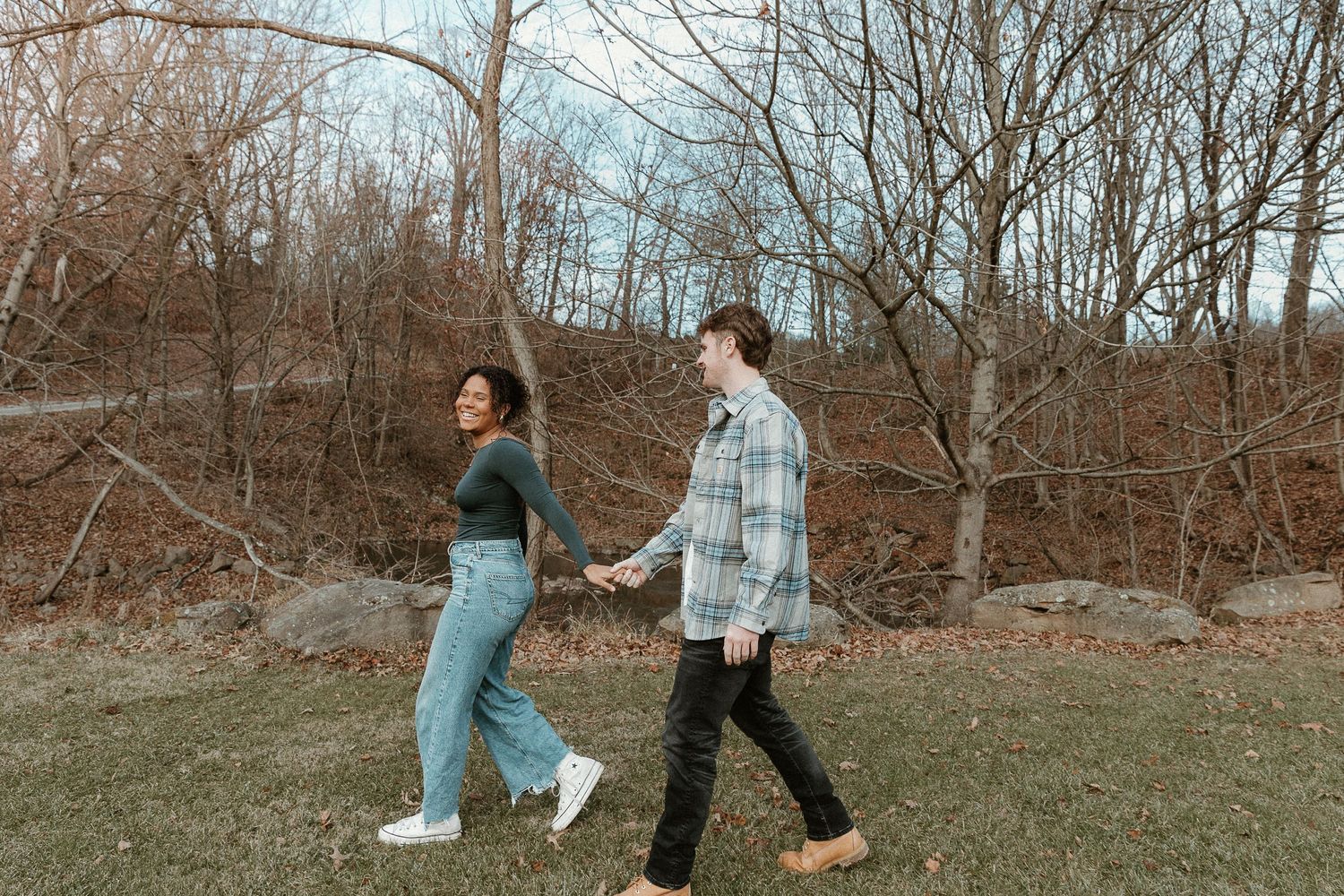 Carefree couple walking hand-in-hand through a park, storytelling-style edit with film tones and natural connection.