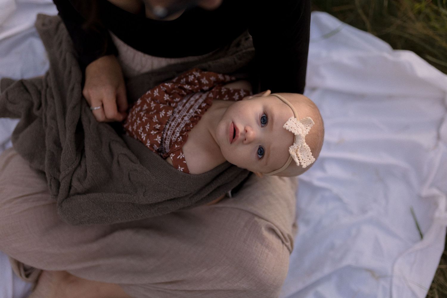 Child resting peacefully on blanket outdoors with bandage on face.