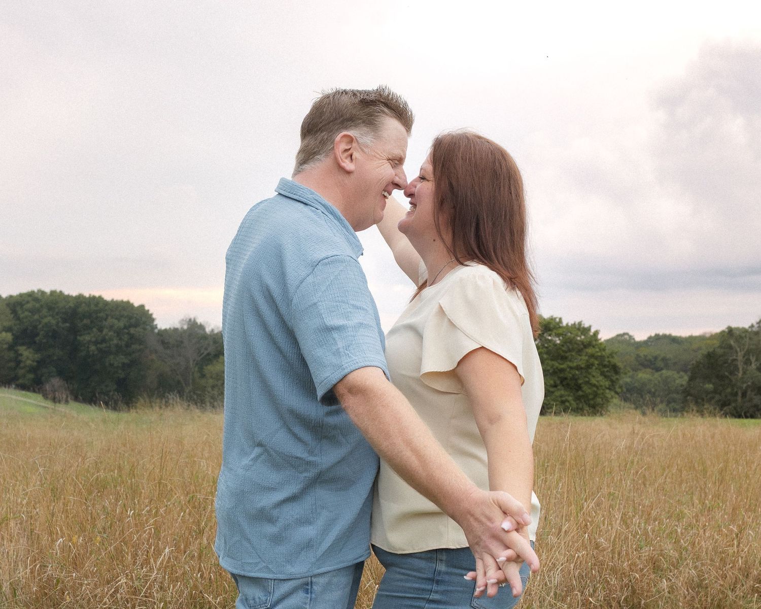 A couple embraces romantically in a golden wheat field during sunset, creating a dreamy outdoor photoshoot moment.