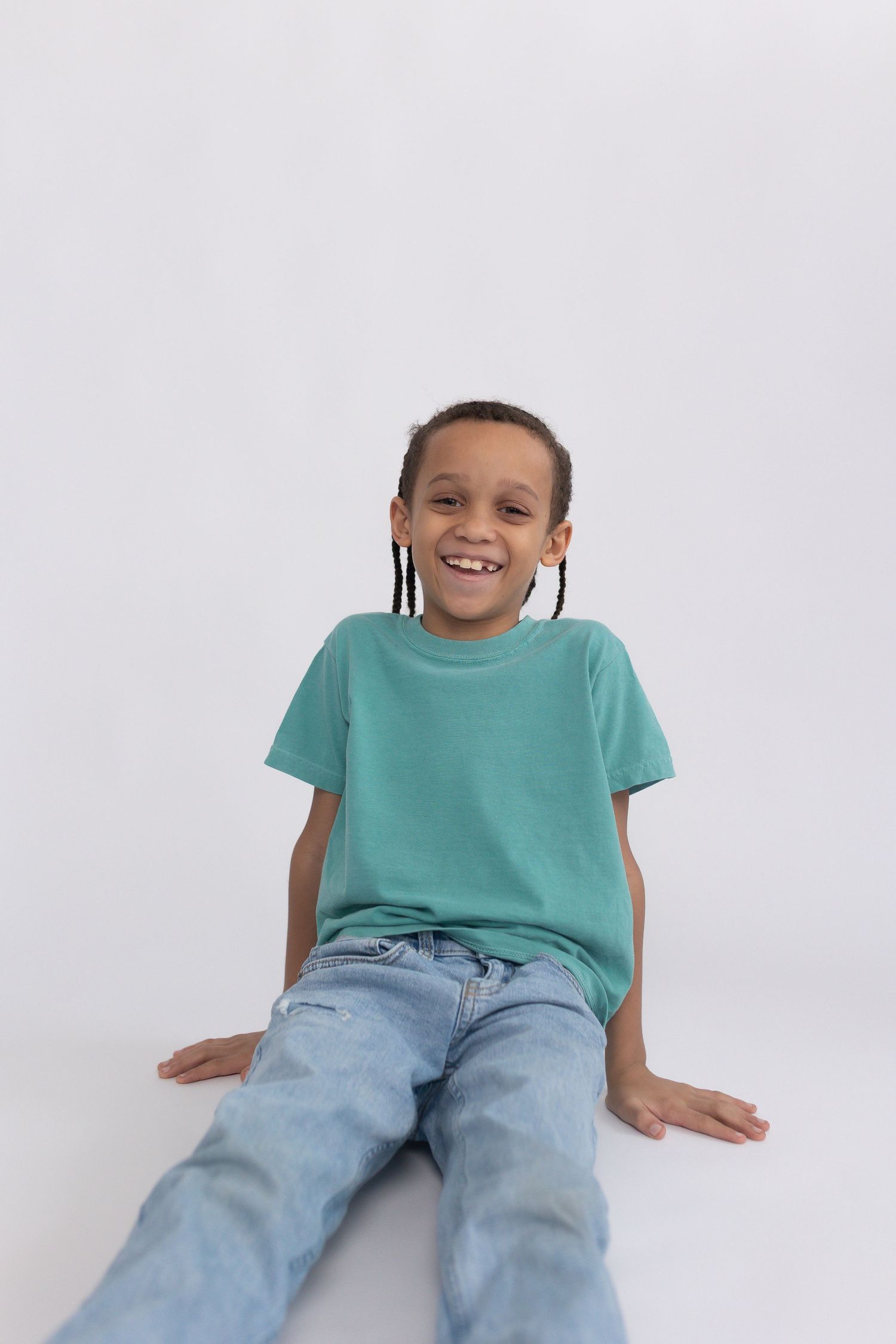 Bright studio portrait of a smiling boy in a green tee and jeans, clean backdrop and modern lifestyle school photo look.