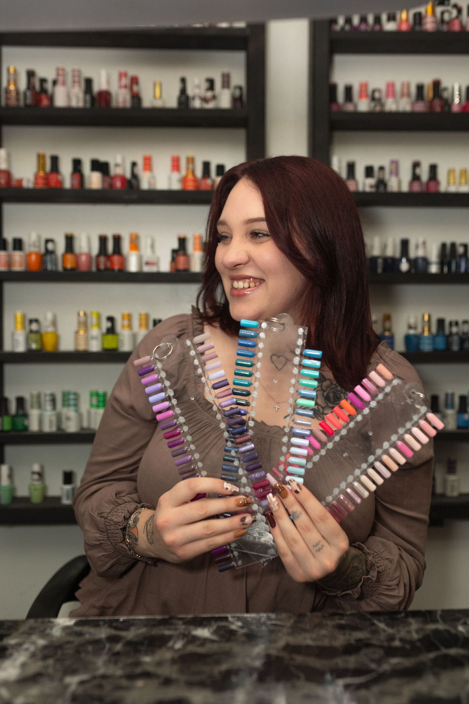 Beauty professional displaying colorful nail polish swatches in salon setting.