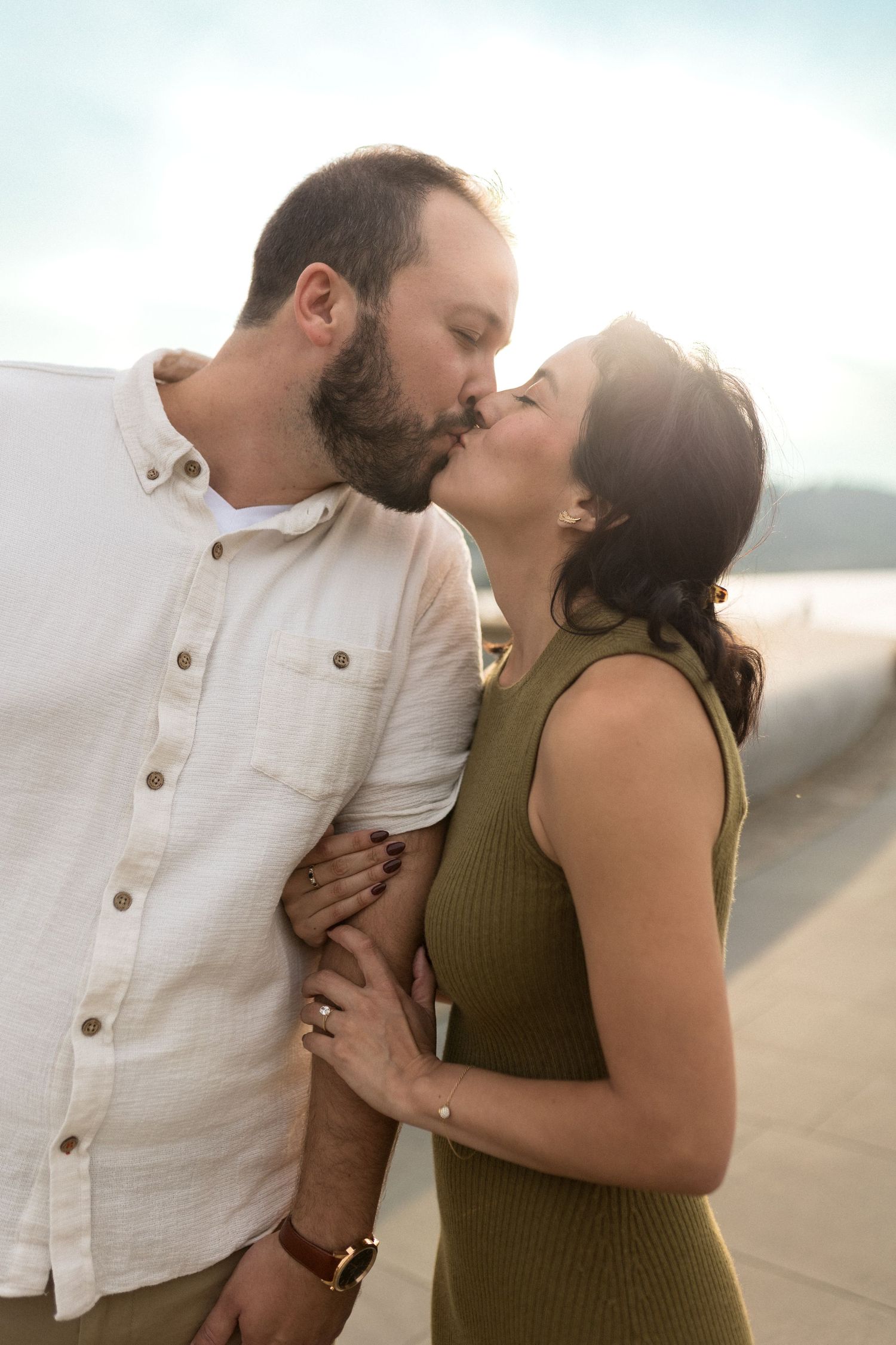 Intimate couple embracing and kissing on beach at sunset.