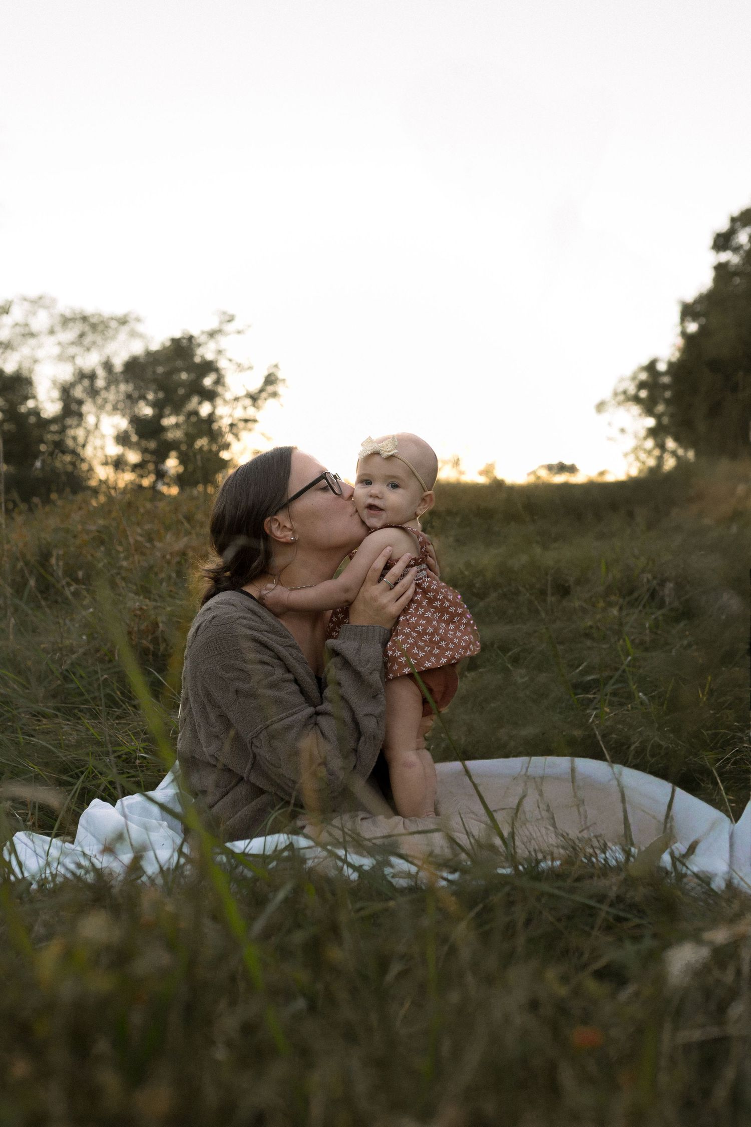 A heartfelt moment shared between two people sitting on a white blanket in tall grass.