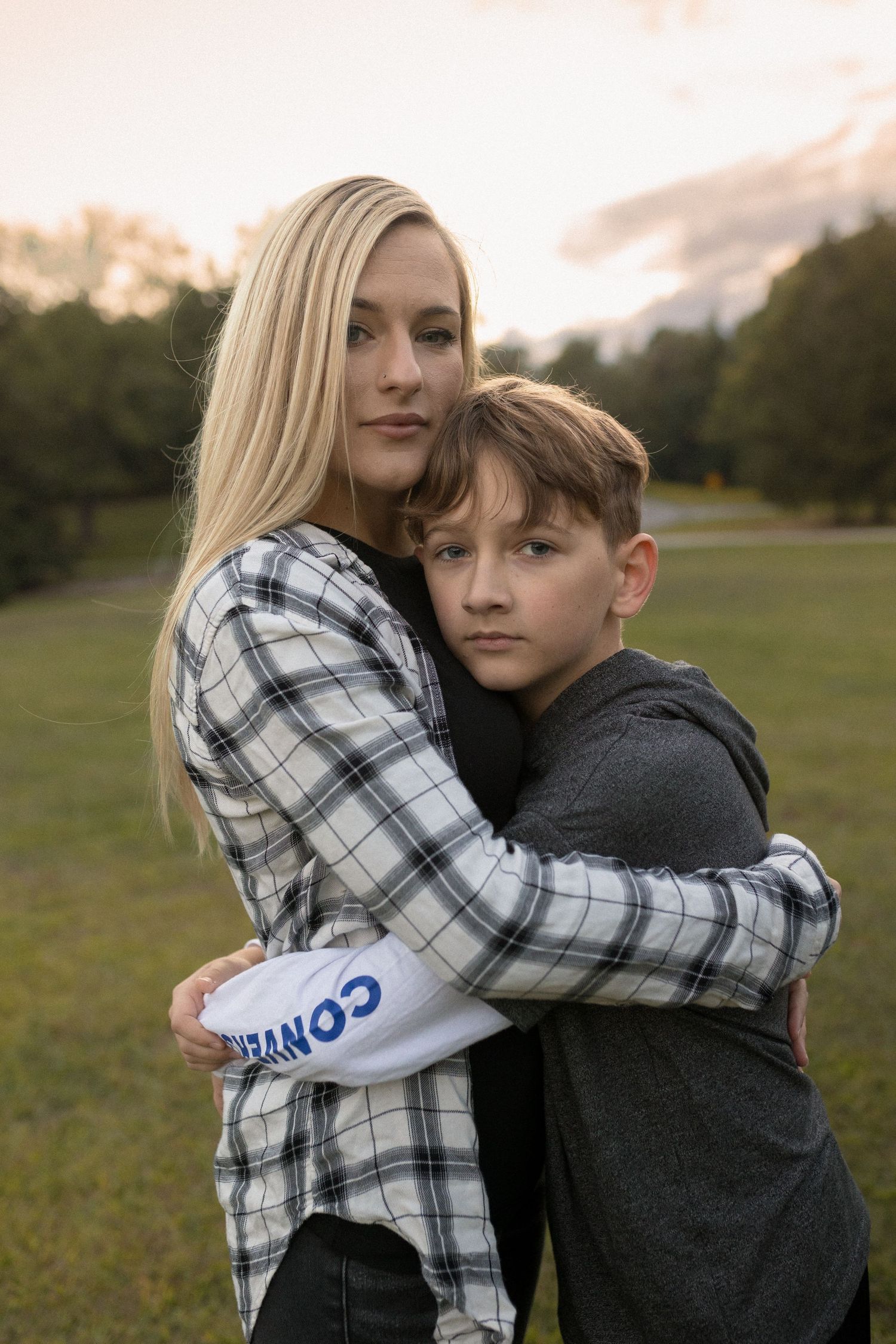 Tender embrace between two people wearing plaid and grey on an autumn evening.