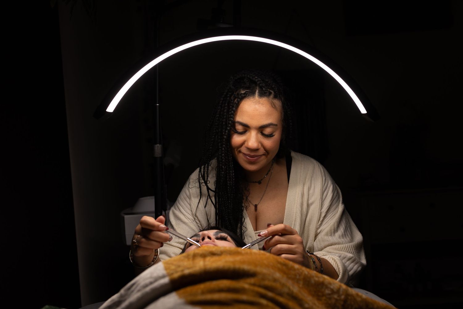 Person looking at phone under curved neon light in dark setting.