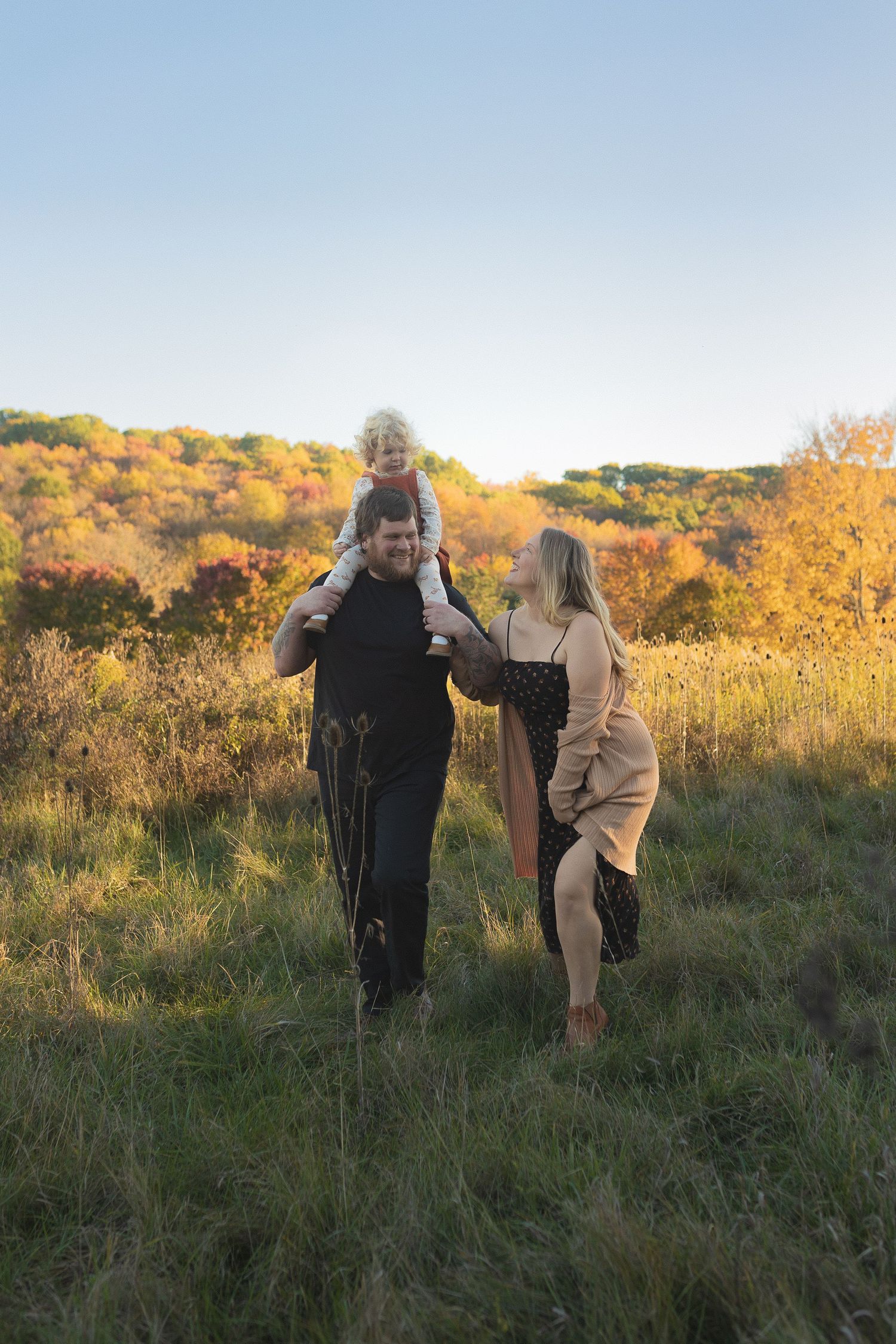 A family walks together through autumn fields during golden hour.