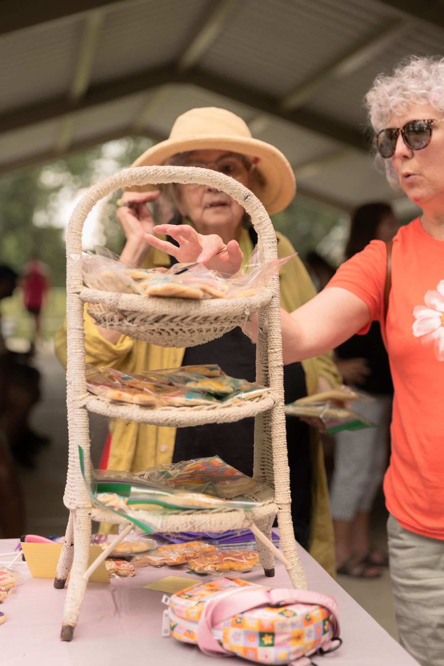 People examining a decorative tiered display stand at an outdoor event.