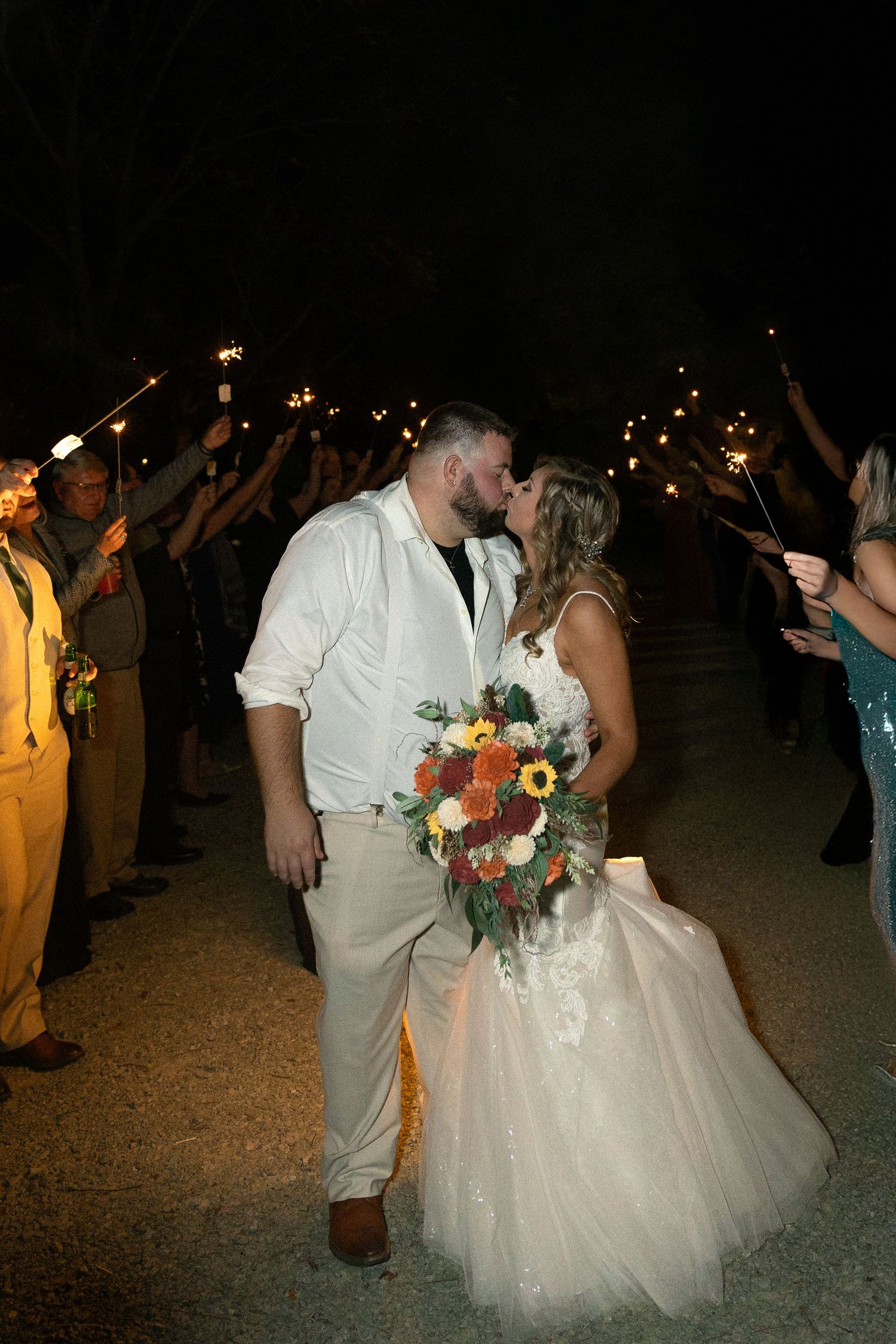 A nighttime wedding exit with sparklers as couple shares romantic moment.