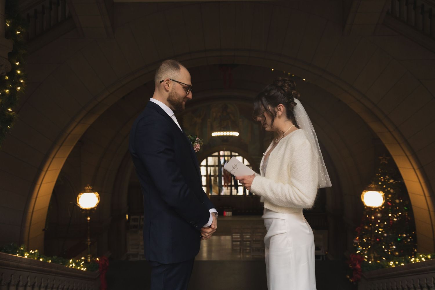 A wedding ceremony under an arched doorway with soft lighting and holiday decorations.