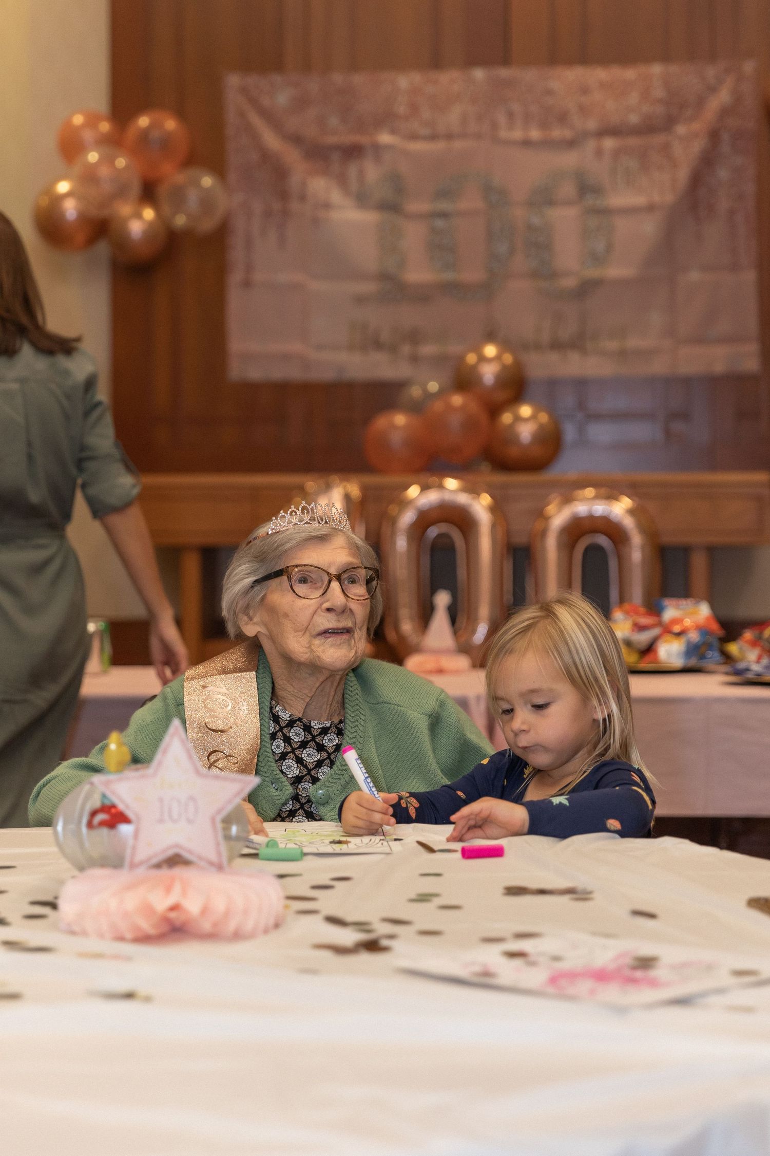 A heartwarming moment shared at a celebration table with decorative balloons in the background.