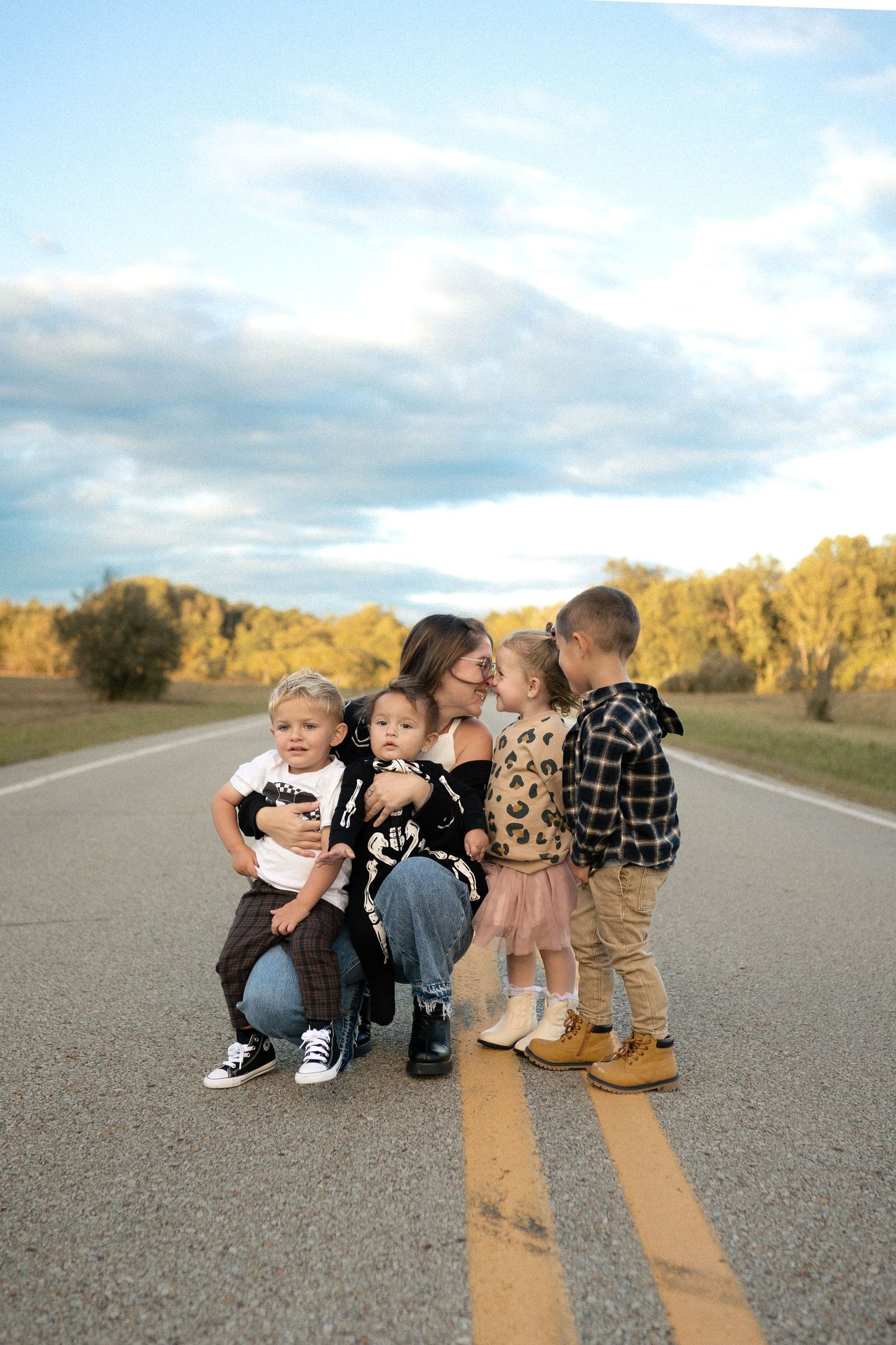 Family gathering on a rural road with yellow lines during golden hour.