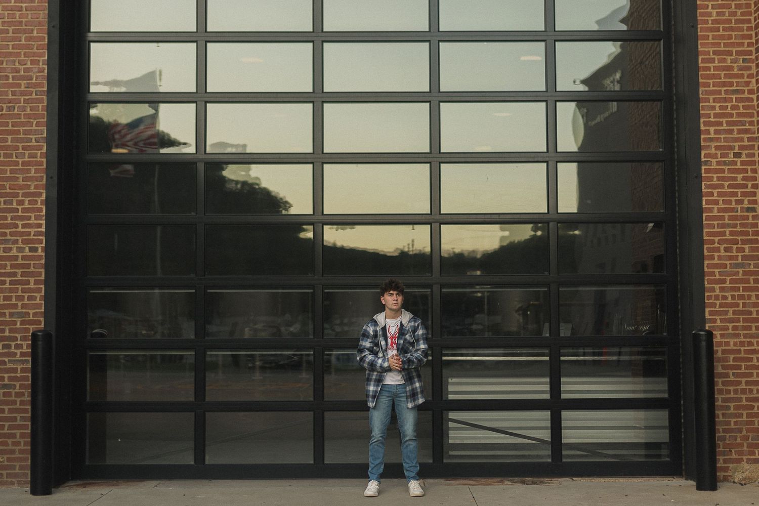Person stands in front of modern glass building entrance at dusk.